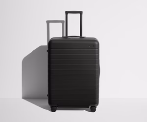 Front product view of The Medium suitcase in Jet Black with raised handle